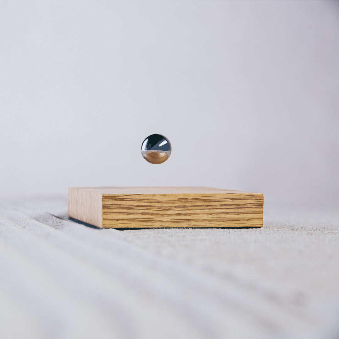 Levitating sphere Buda Ball by Flyte, chrome sphere, oak base version in a zen garden setting