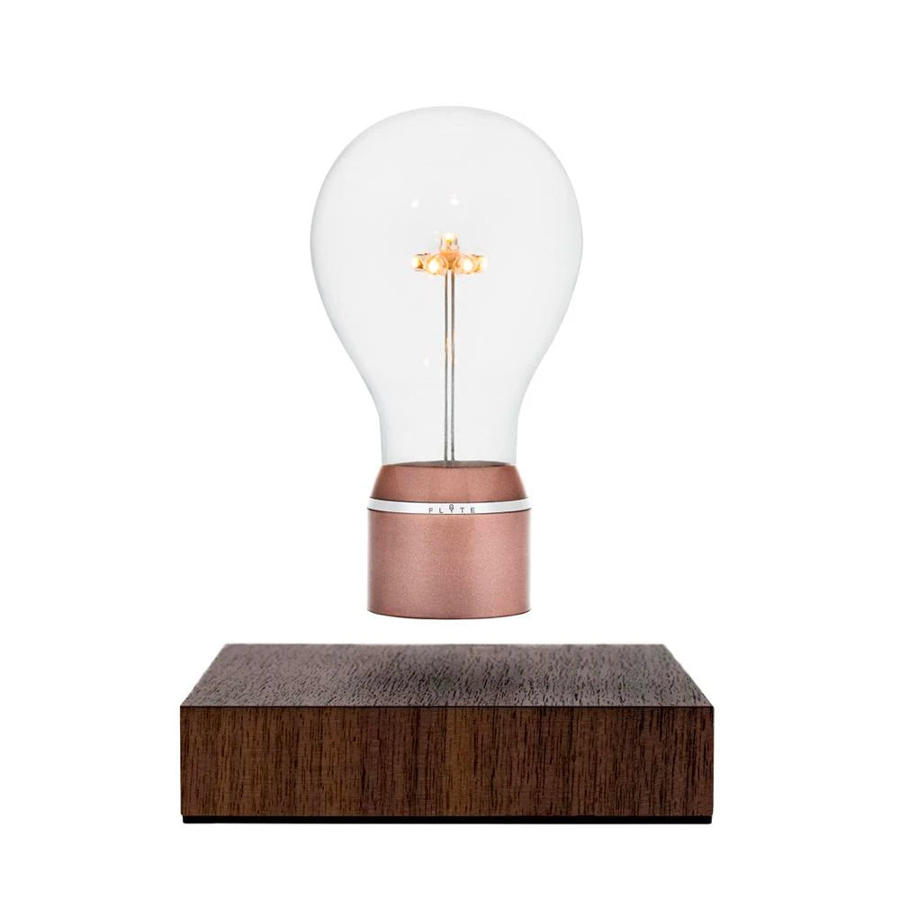 Product photo of levitating light bulb Light by Flyte, walnut wood magnetic base with copper cap bulb on a white background