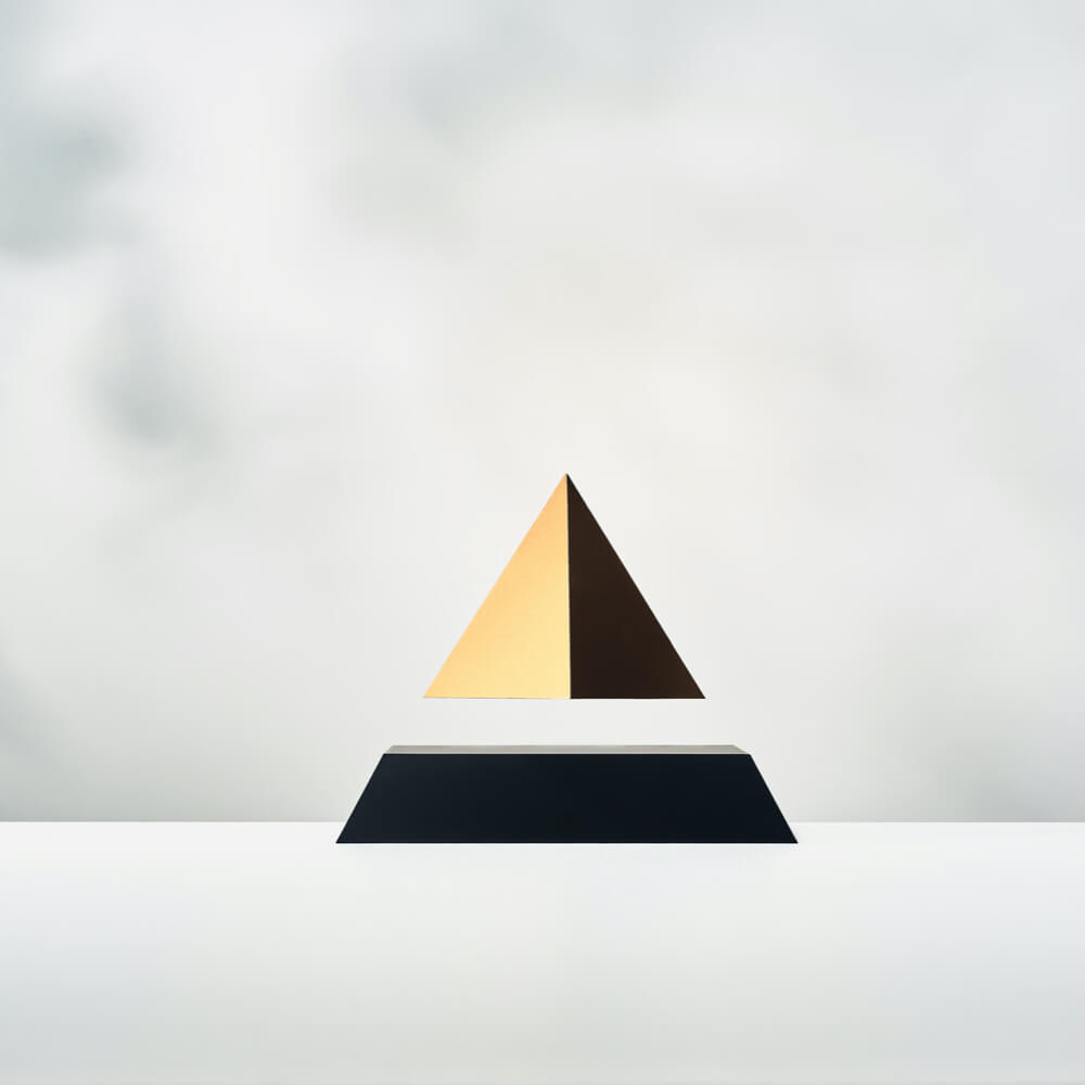 Levitating pyramid Py by Flyte, gold top on a black base, light background