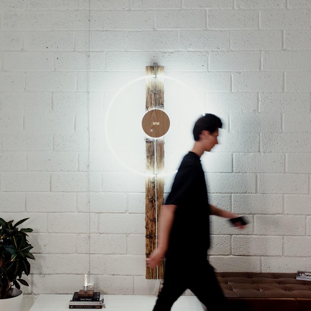 Story oak, levitating clock hanging on a white wall with man walking by in front