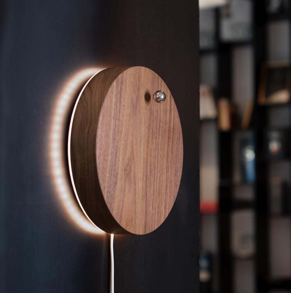 Story walnut - side view of levitating clock hanging on the wall with backlight turned on 