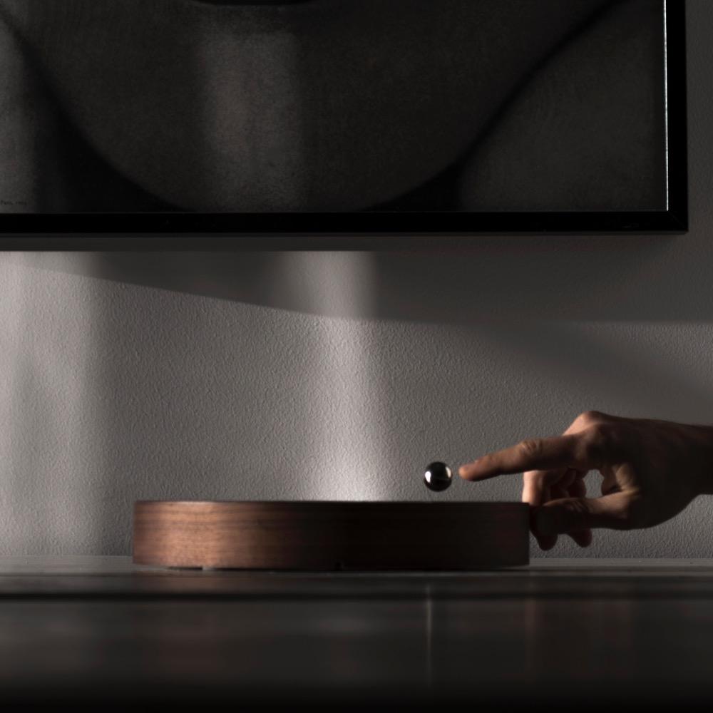 Walnut Story - levitating clock horizontally on the table with ball hovering in the air 